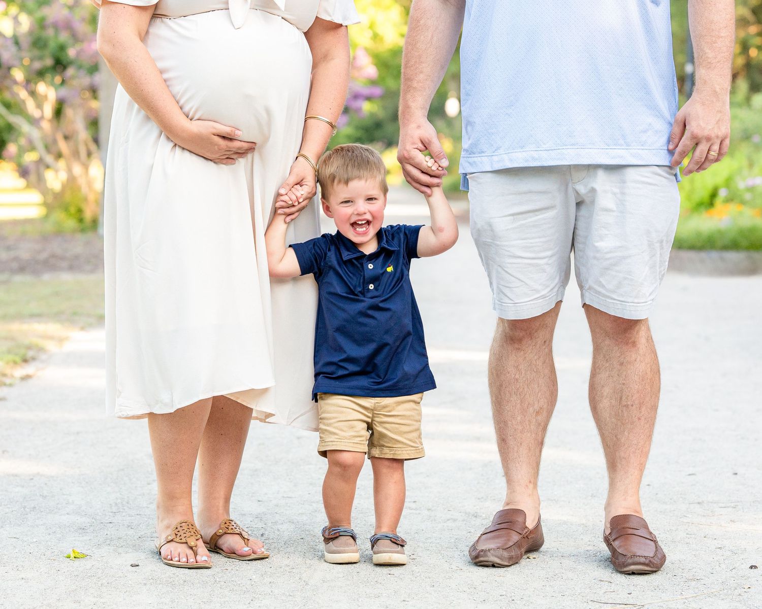 A cropped photo highlighting mom's pregnant belly while holding hands with her happy toddler