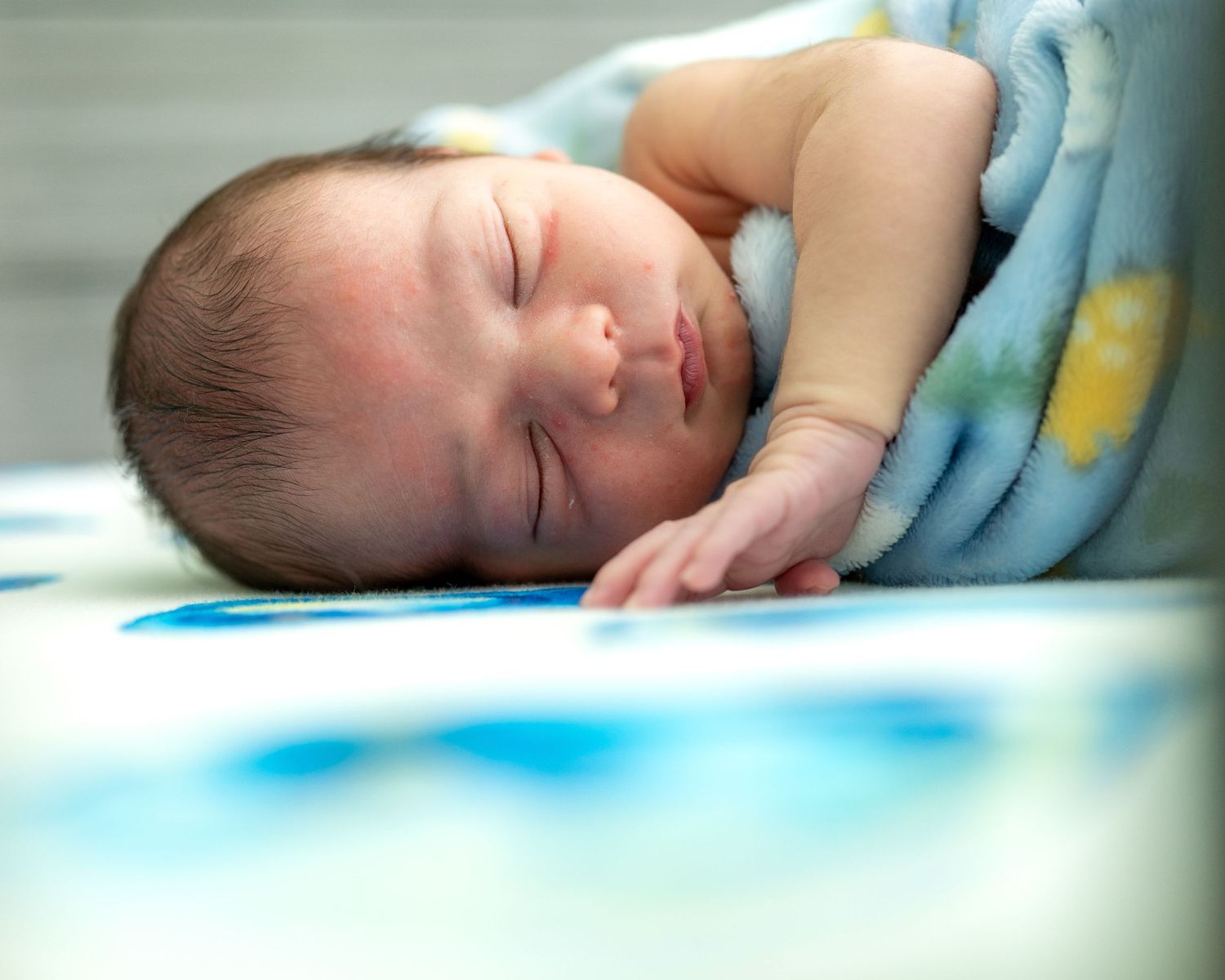 A peaceful sleeping newborn baby wrapped in a soft blue blanket.