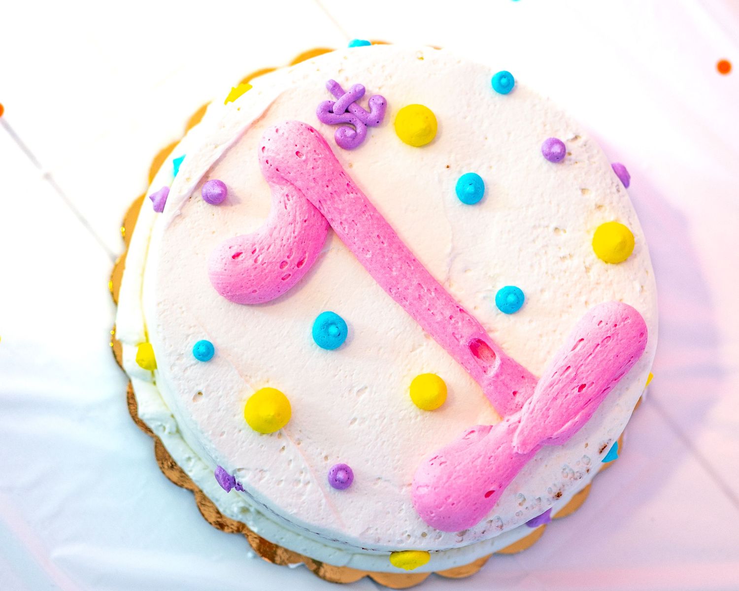 Close up of a round smash cake with multi colored polka dots and a big pink number one
