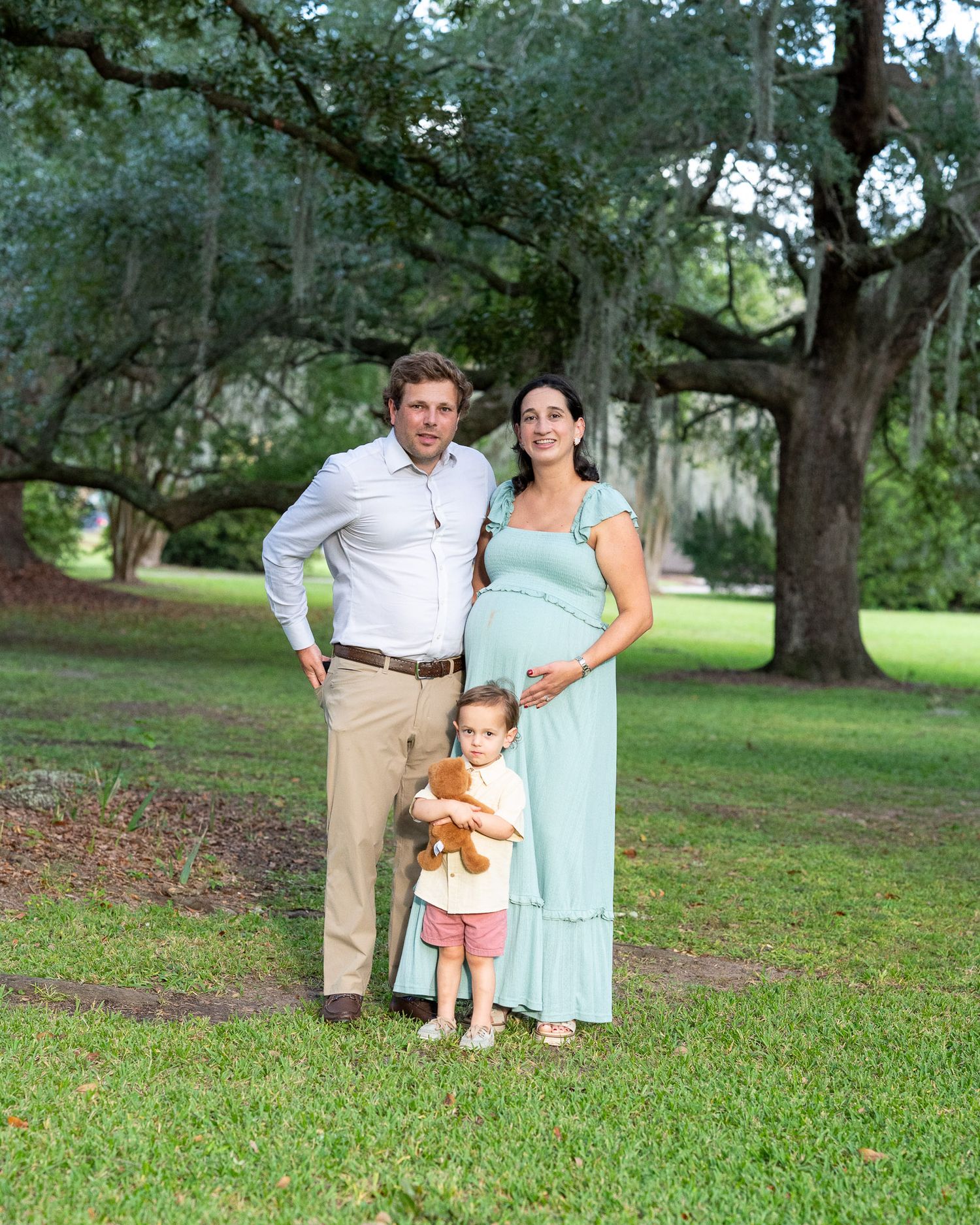 Unedited maternity family photo session in a park with Spanish moss draped oak trees creating a natural outdoor backdrop.