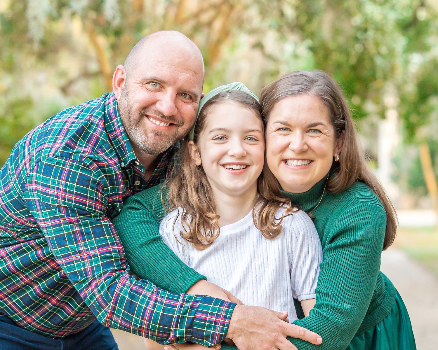Family members share joyful moments together in a casual outdoor photo session with green surroundings.