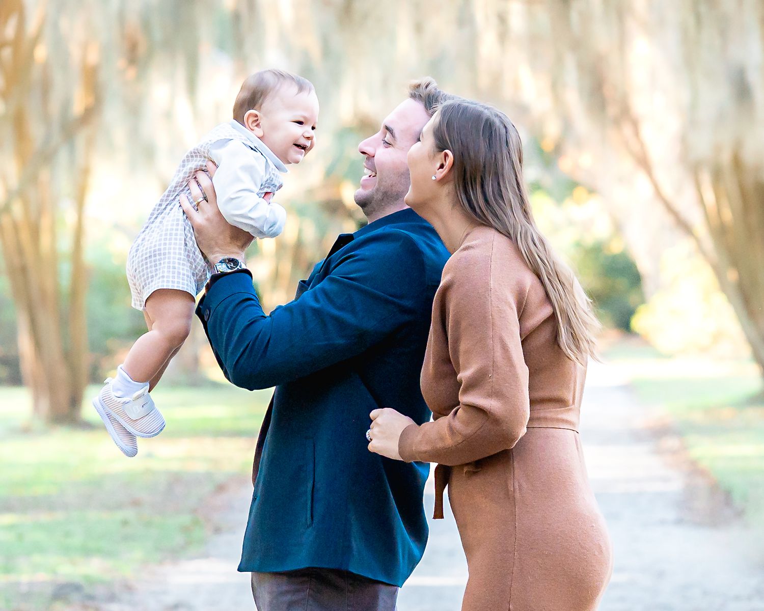 A tender family moment captured outdoors with soft natural lighting and neutral earth-toned clothing.