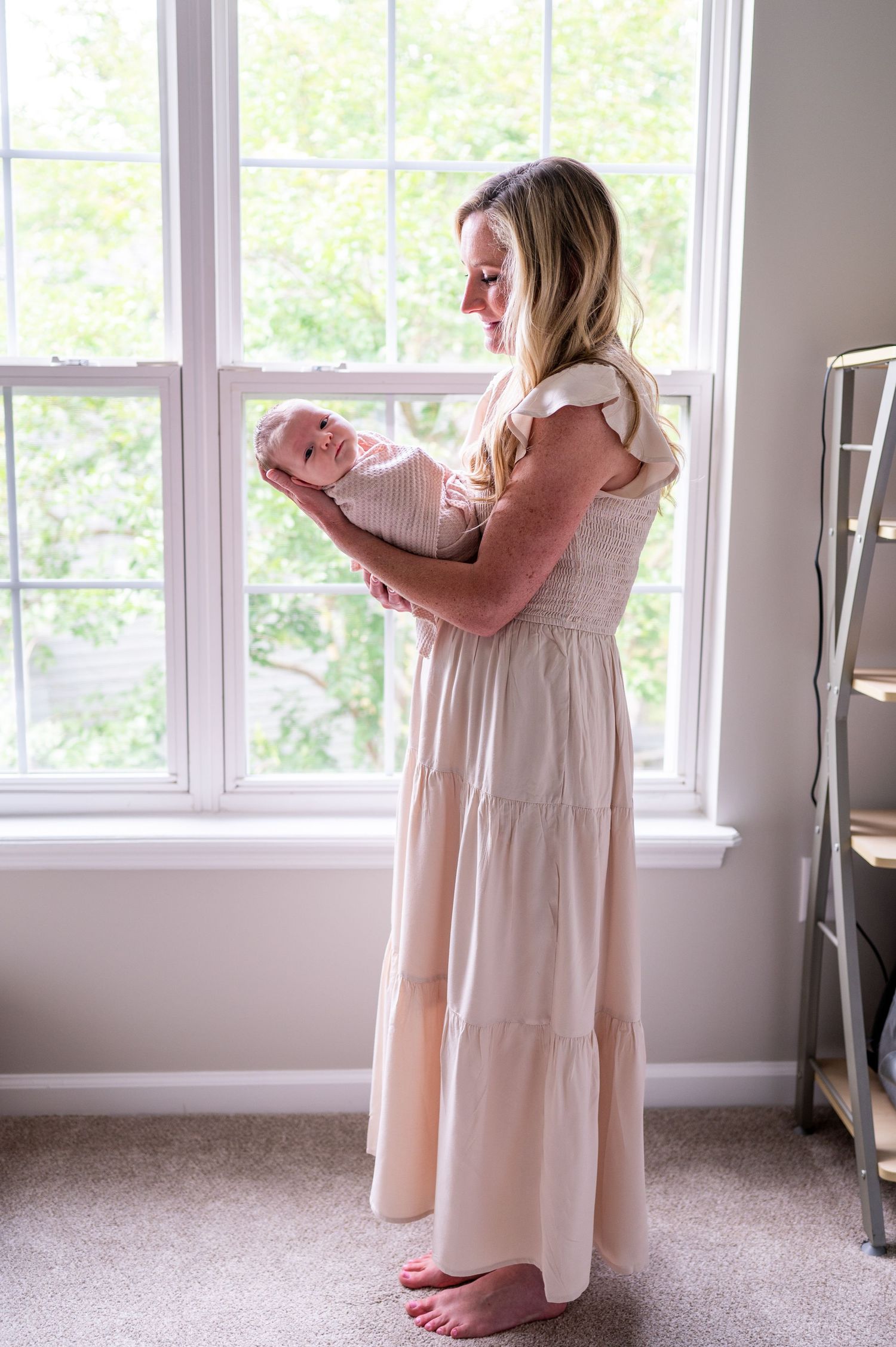 Meghan holds her newborn daughter who looks at the camera with a sleepy expression