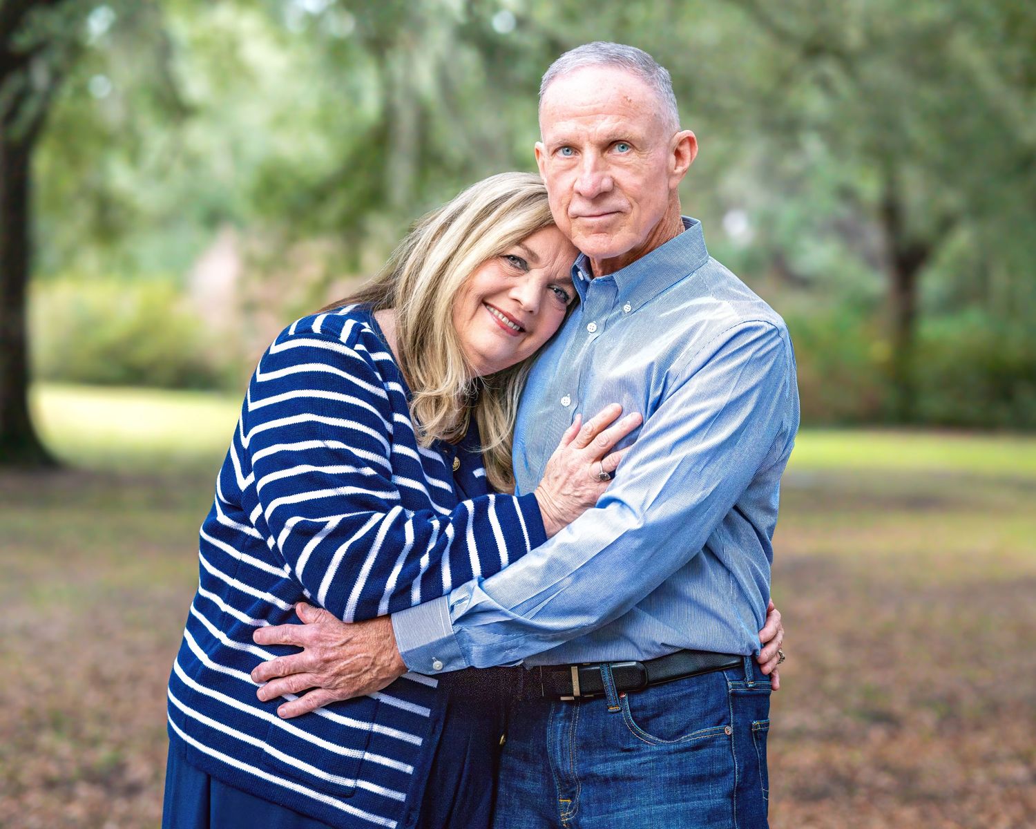 A couple in blue and white stripes embracing outdoors in a natural setting.