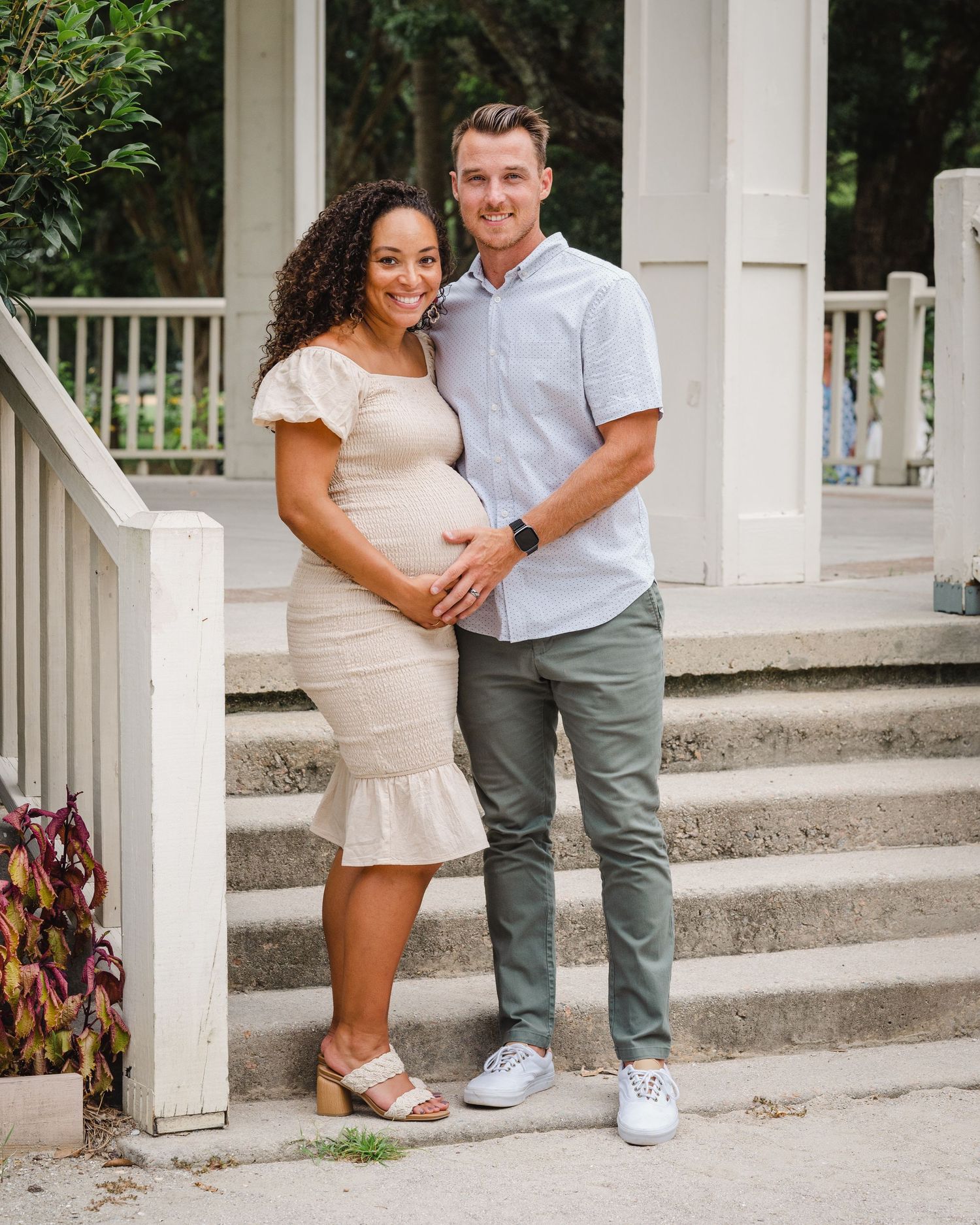 Keirstan and Rob stand in front of the gazebo at Hampton Park each touching Keirstan's pregnant belly.