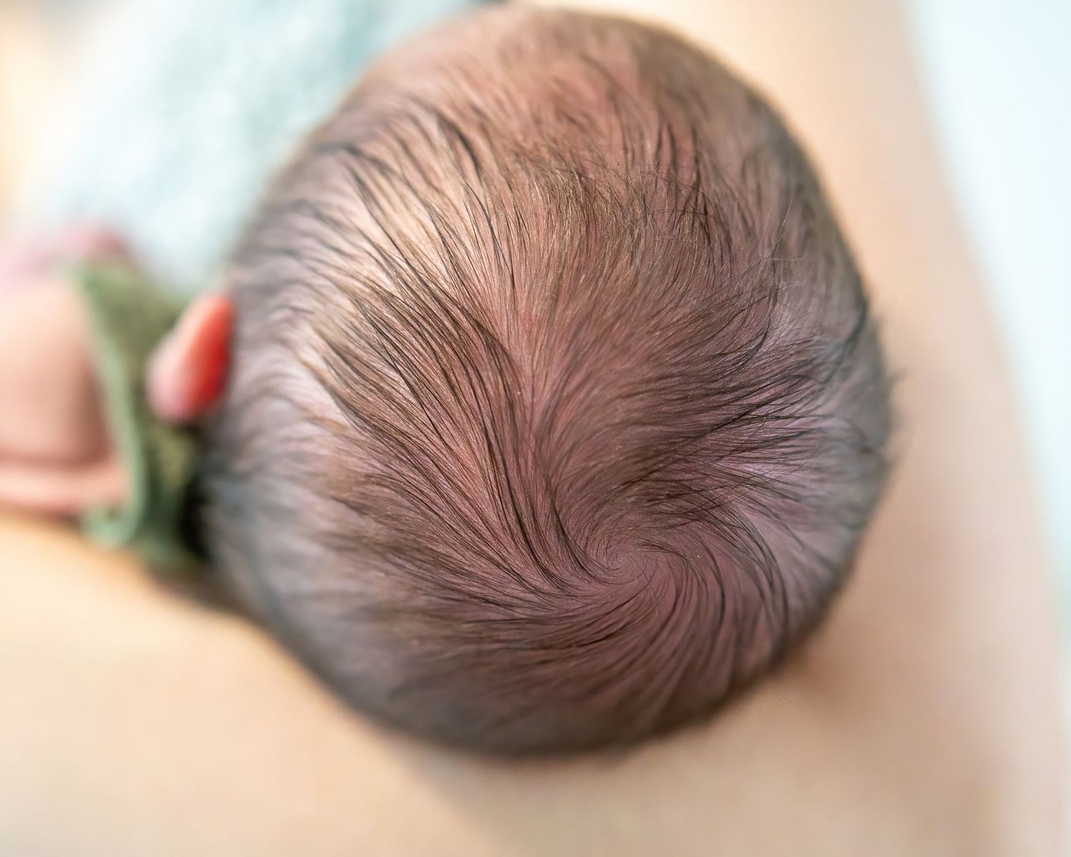 Close up view of a newborn baby's swirling hair pattern on top of their head.