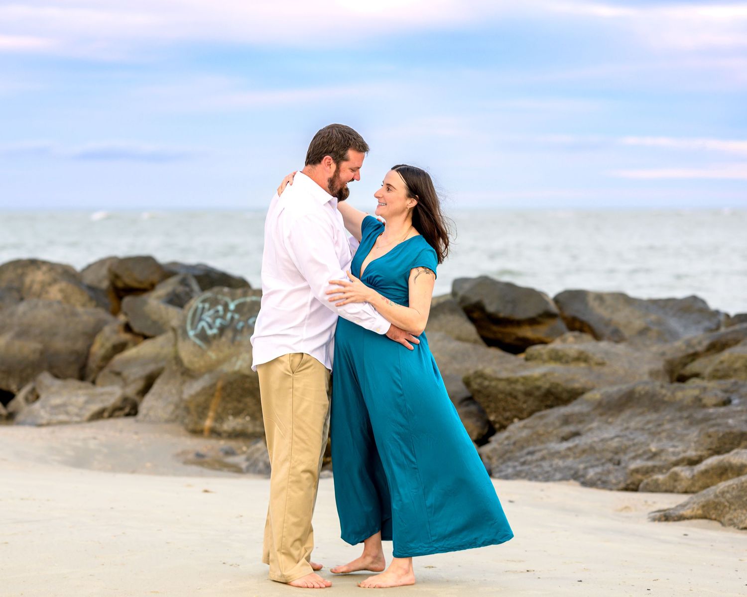 Expecting couple dancing at beach