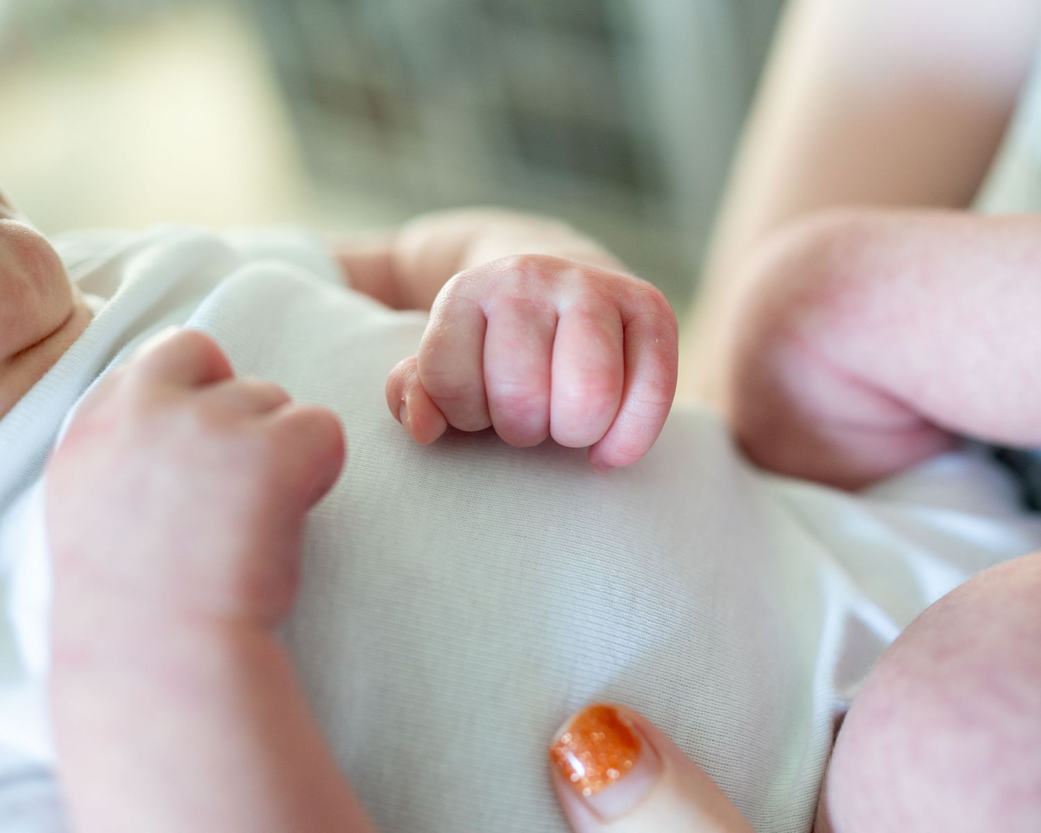 Close-up view of tiny infant fingers against a white background.