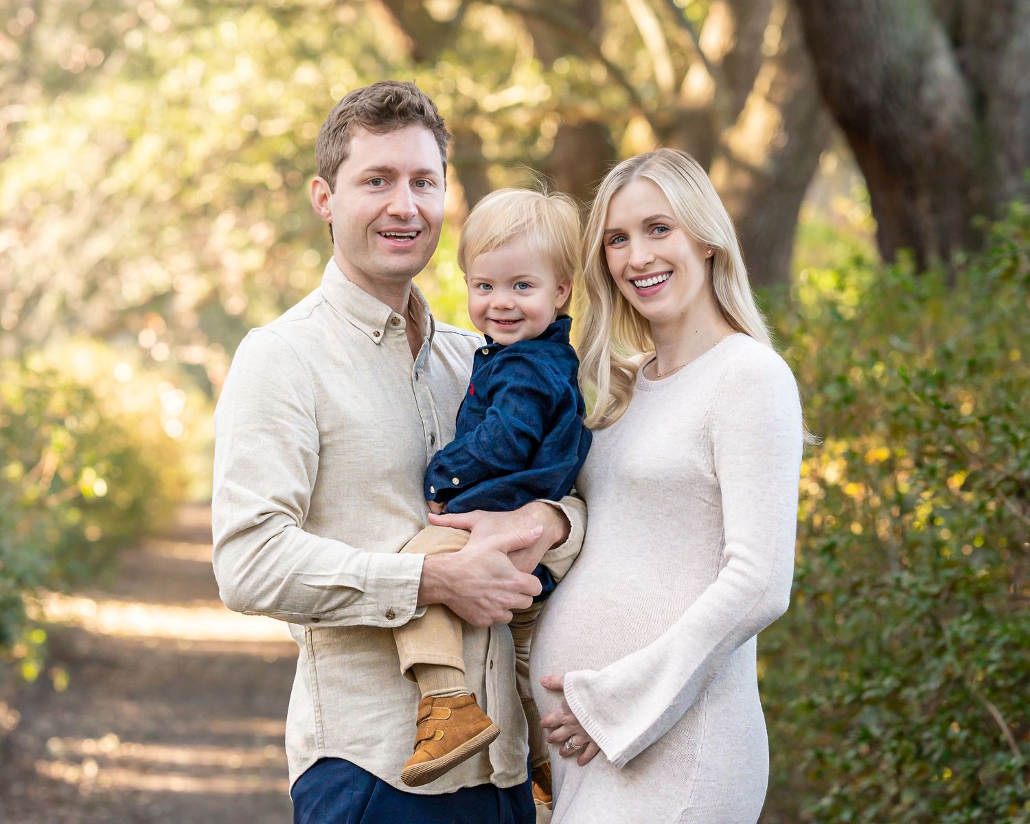 Family portrait session in a sunlit forest with natural autumn colors.