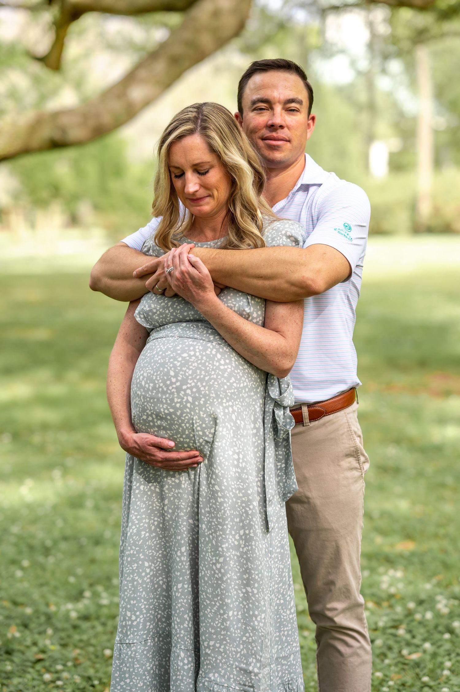 Angel and Arnold stand embraced as Angel holds her swollen, pregnant belly.