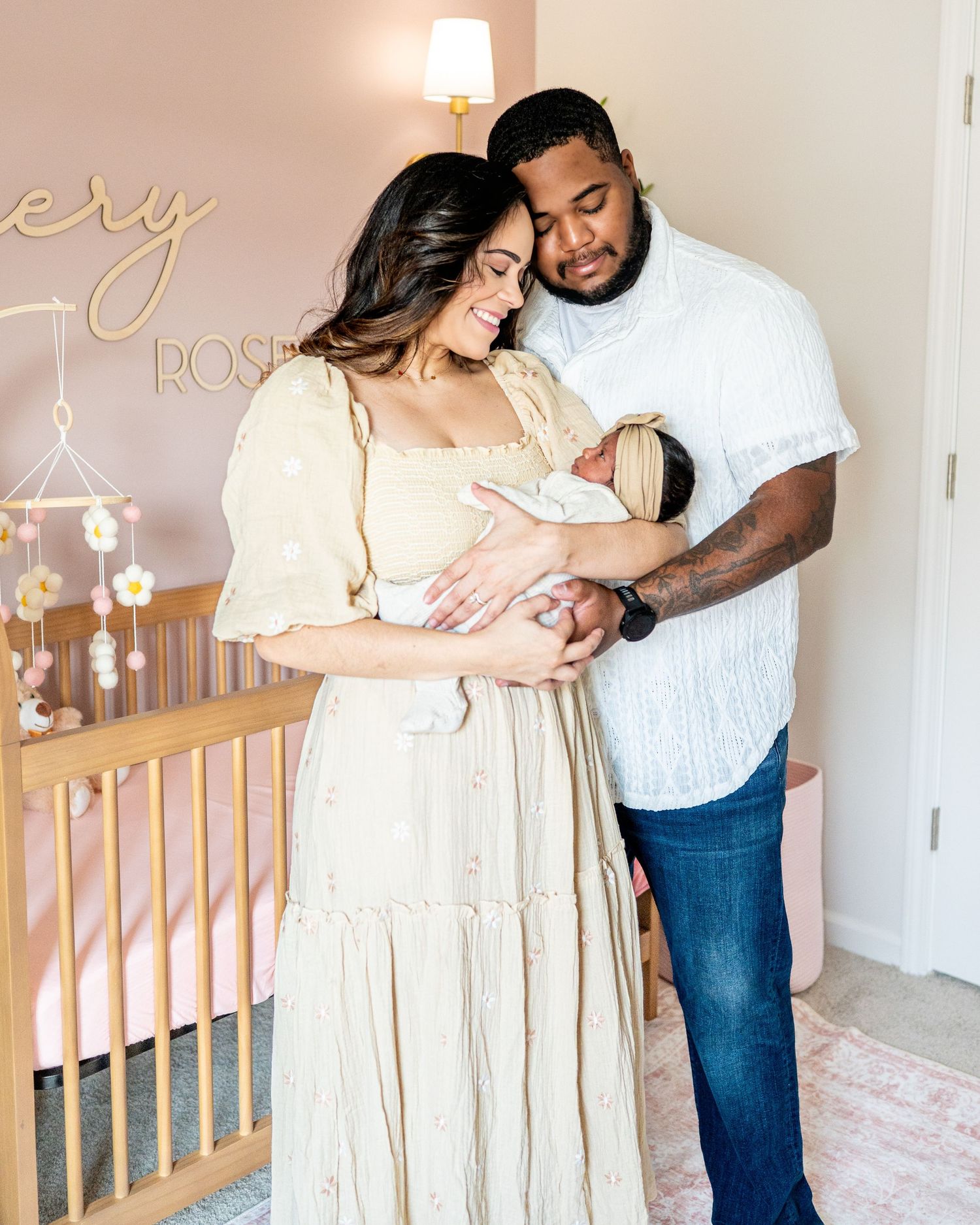 Couple sharing intimate moment while standing in nursery with wooden crib.