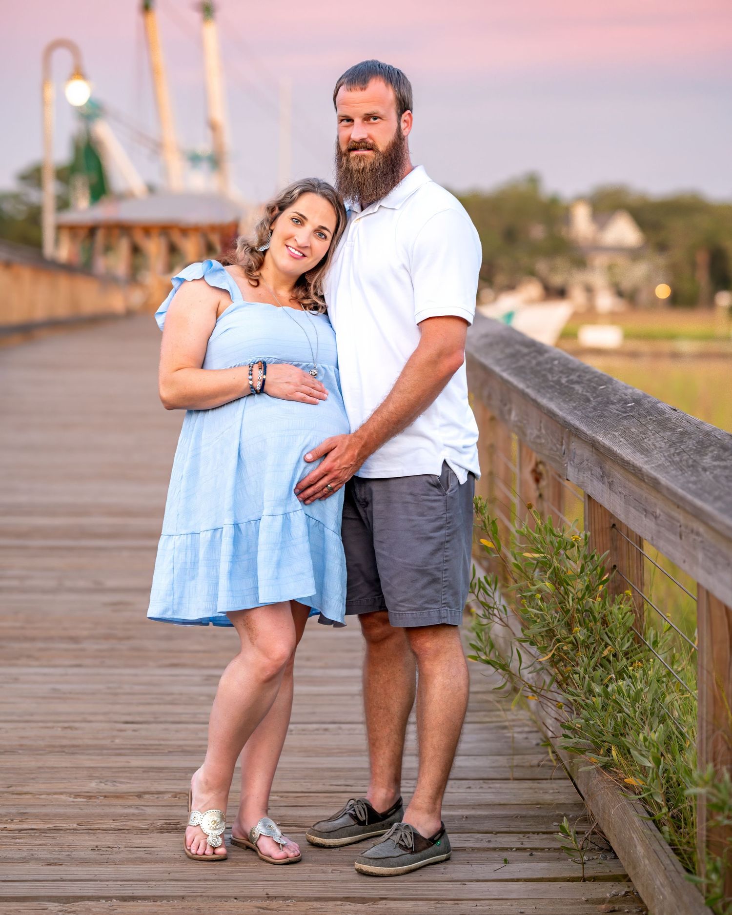 A sweet moment shared on a wooden boardwalk at sunset.