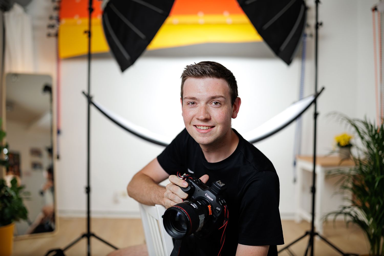 Photography studio setup with lighting equipment and indoor plants against colorful backdrop. osthofen
