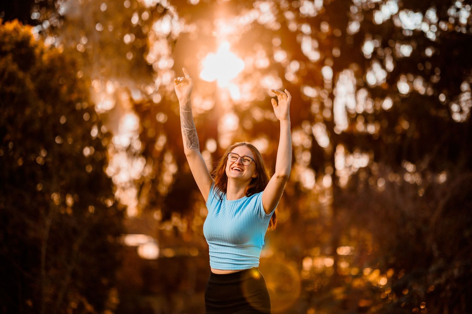 Portait of person in athletic wear celebrating during golden sunset.