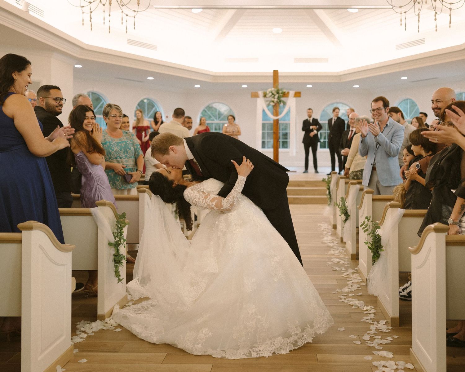 Newlyweds share their first kiss during the ceremony exit, surrounded by cheering guests.