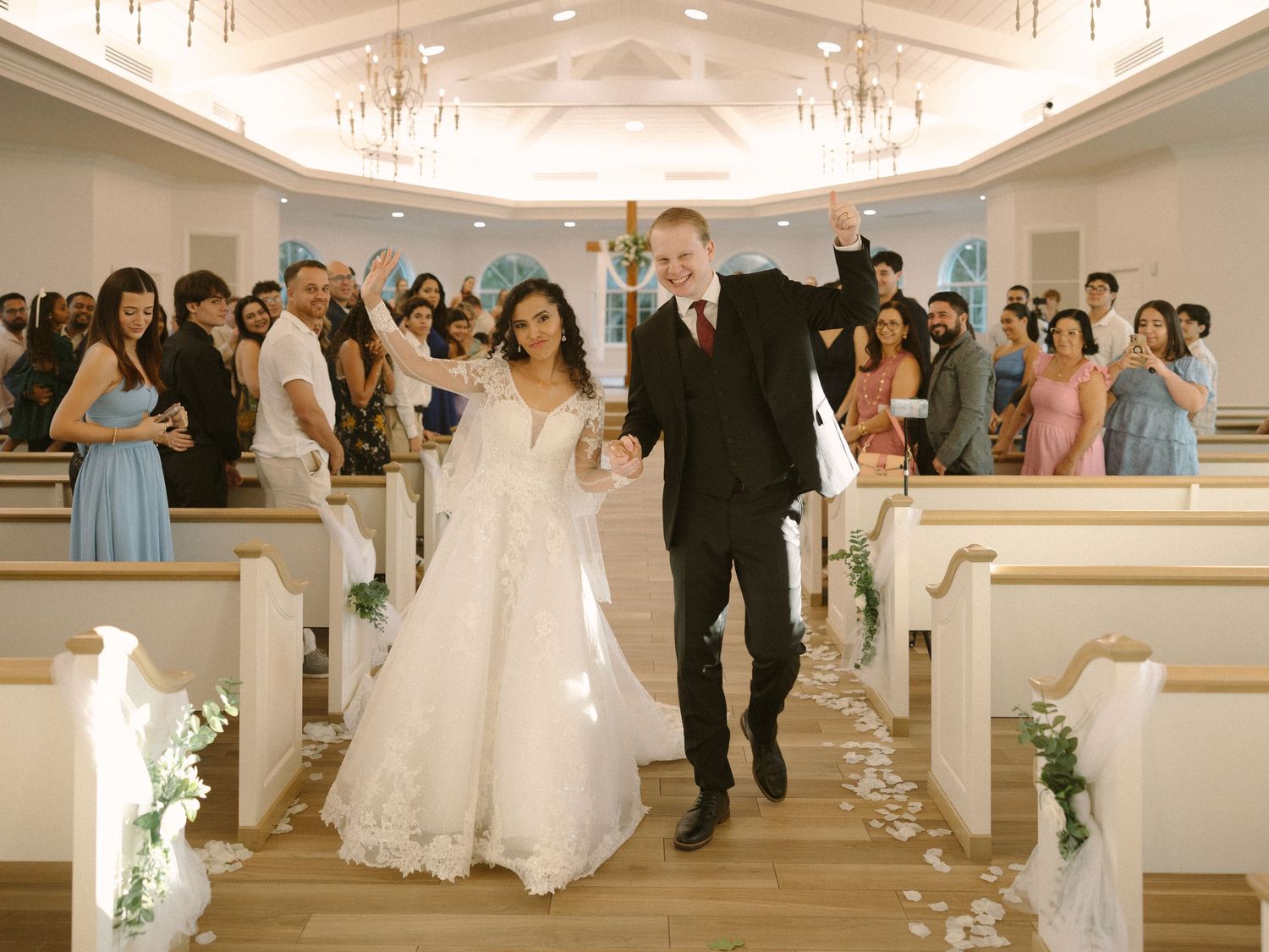 Bride and groom walk down the aisle together after the ceremony, celebrating with friends and family.