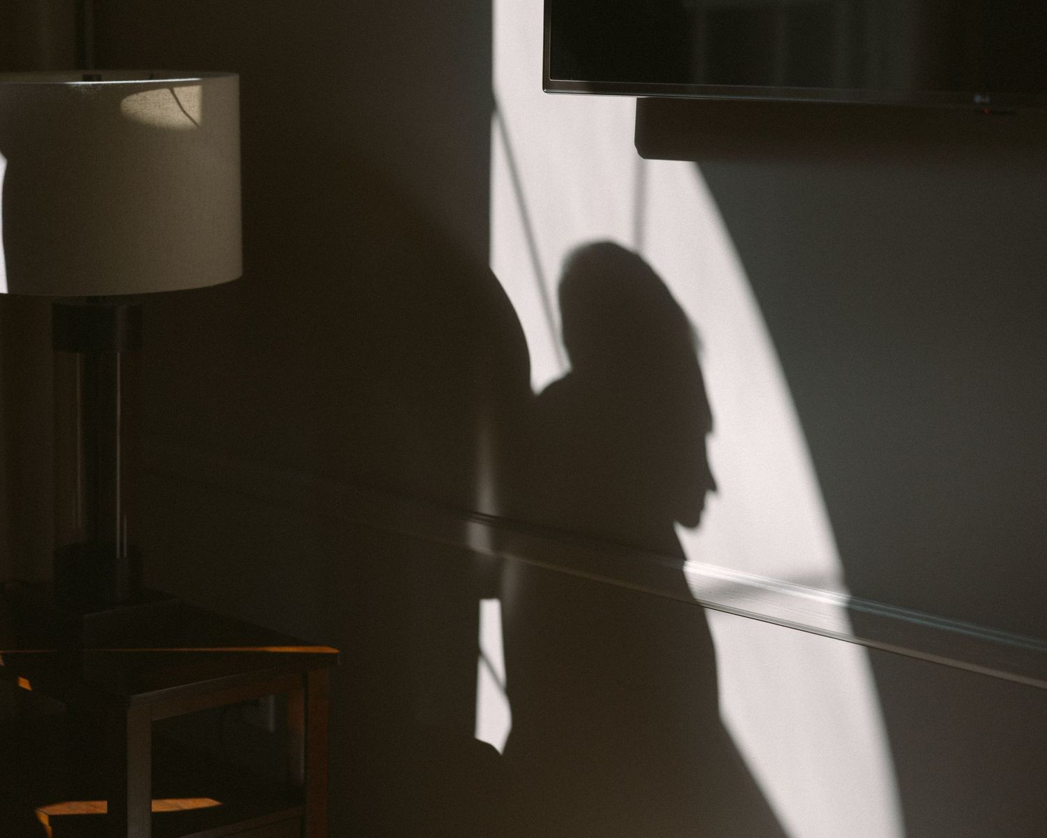 Groom standing by a window in natural light, a quiet, reflective moment before the ceremony.