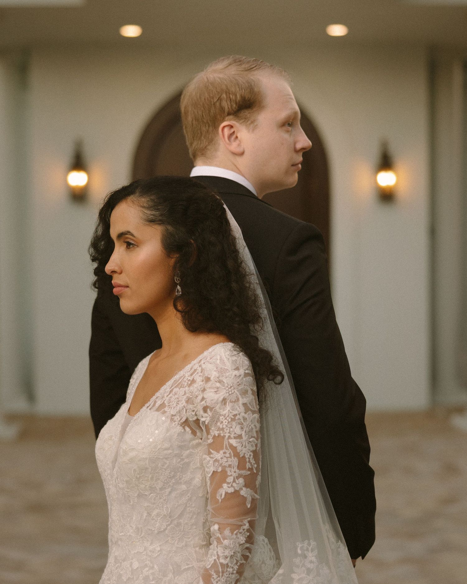 Bride and groom embrace in front of the venue, a timeless portrait with soft, natural tones.