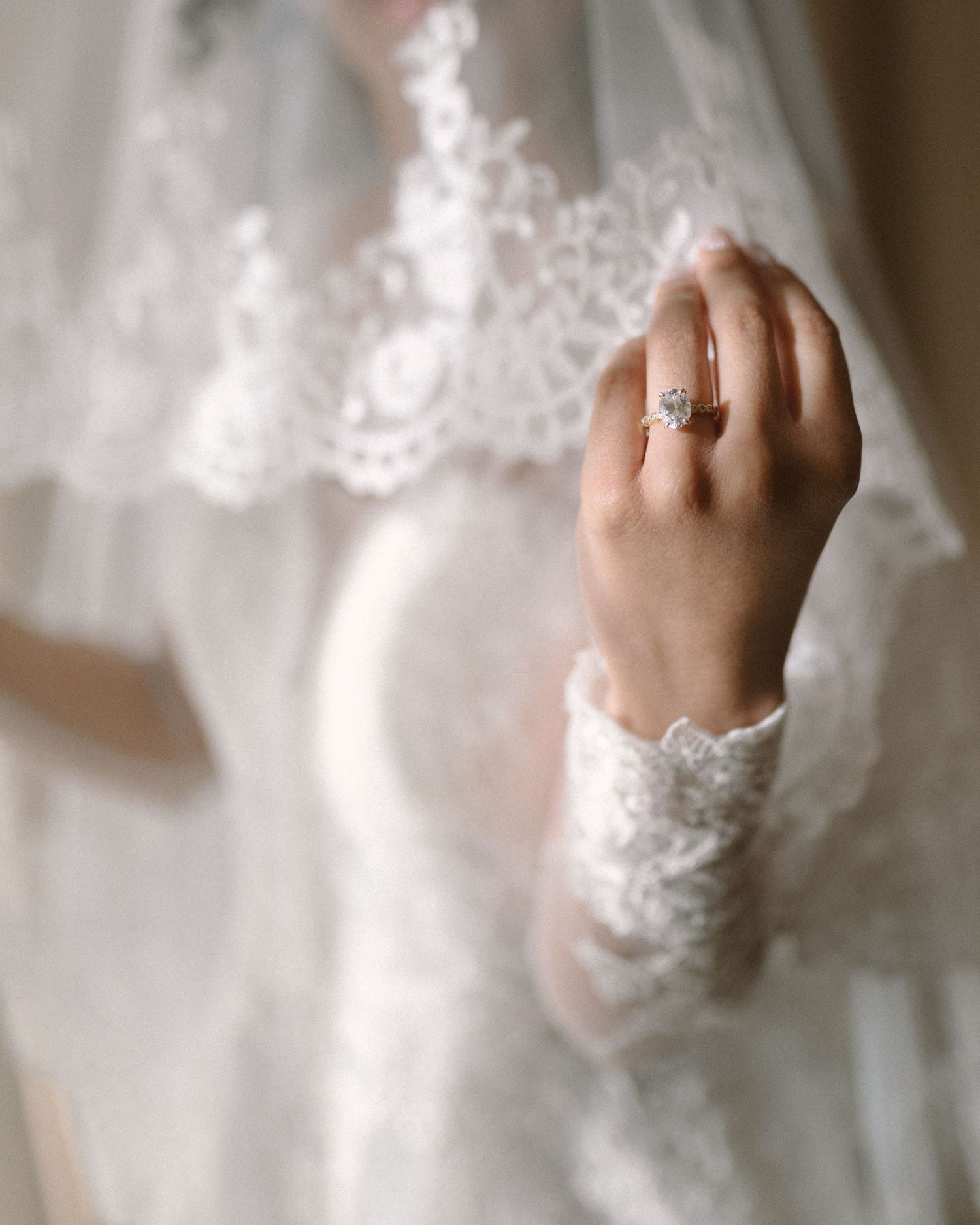 Bride in soft window light, framed through a doorway for an intimate, candid getting-ready moment.