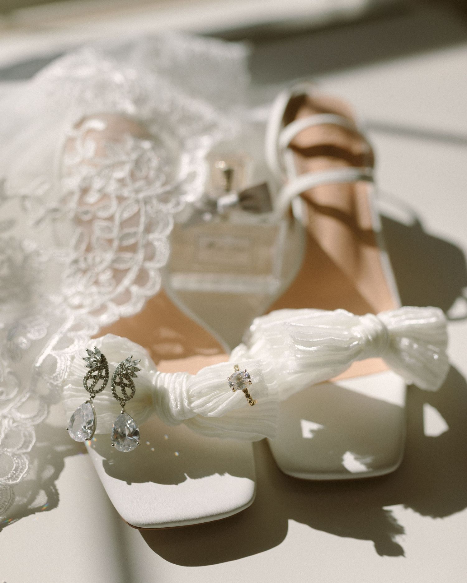 Bride in veil standing by soft drapery, a quiet and emotional portrait capturing anticipation before the ceremony.