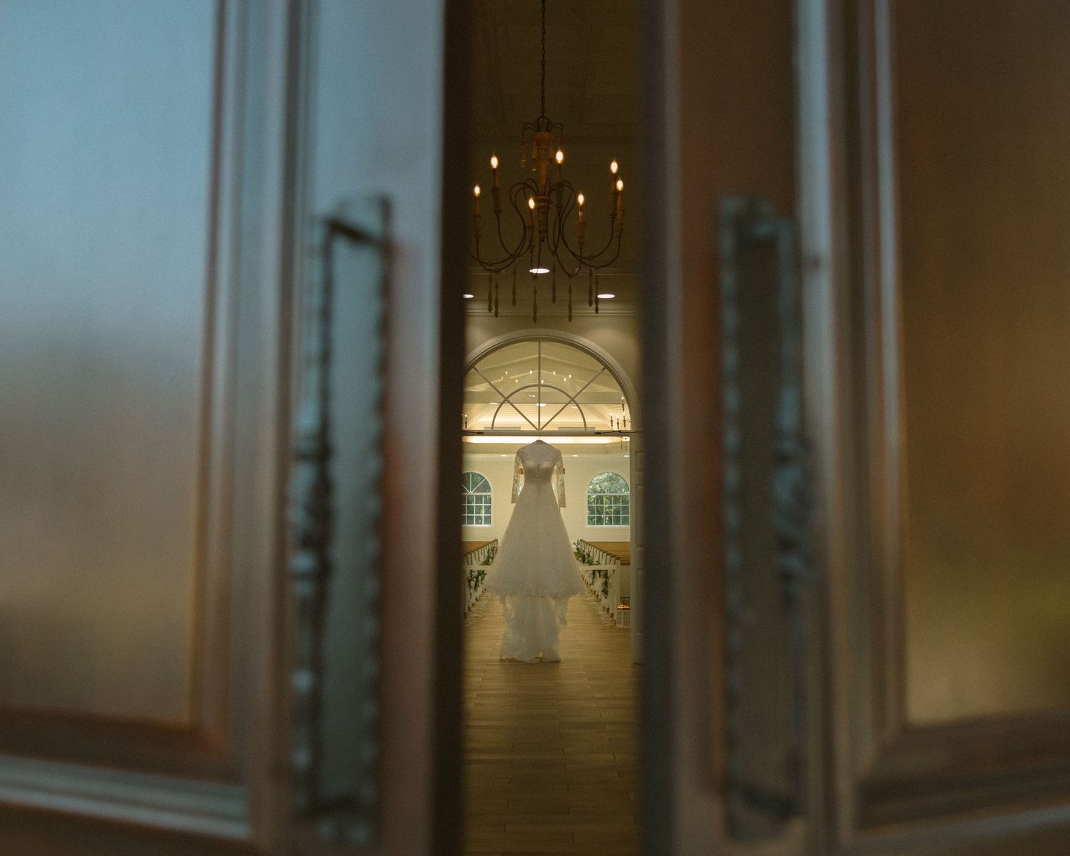 Bride in veil standing by soft drapery, a quiet and emotional portrait capturing anticipation before the ceremony.