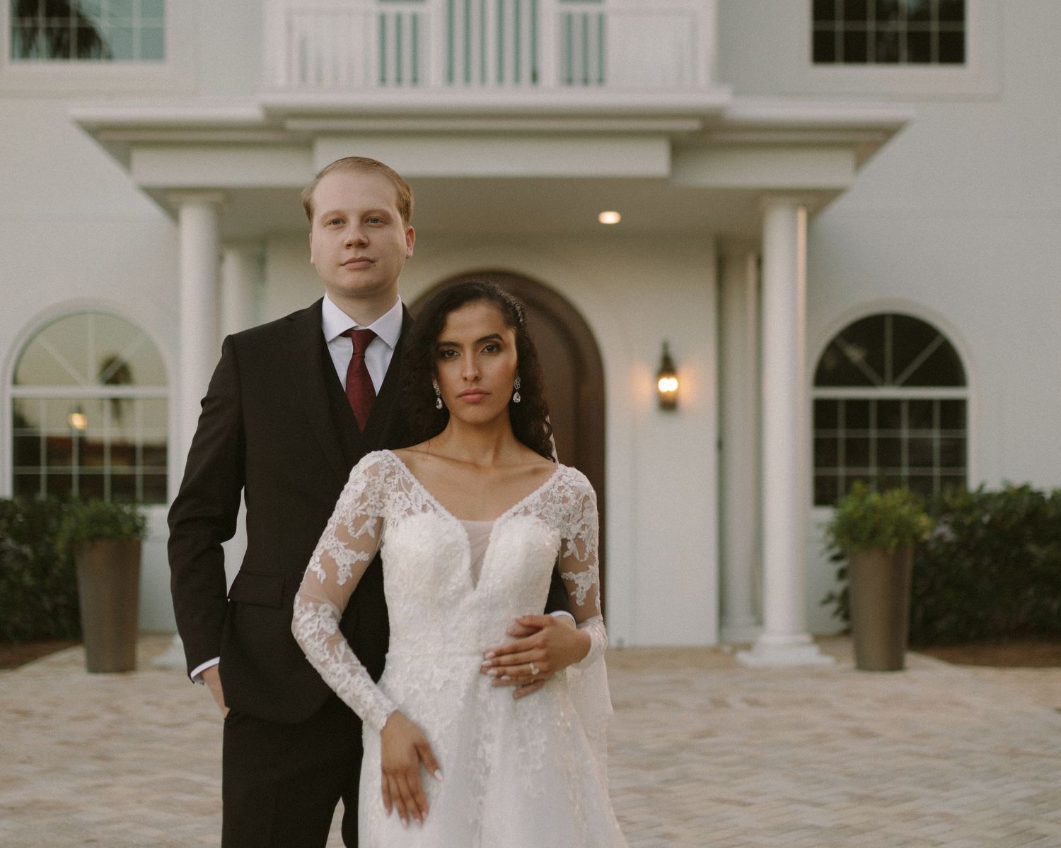 Bride and groom embrace in front of the venue, a timeless portrait with soft, natural tones.