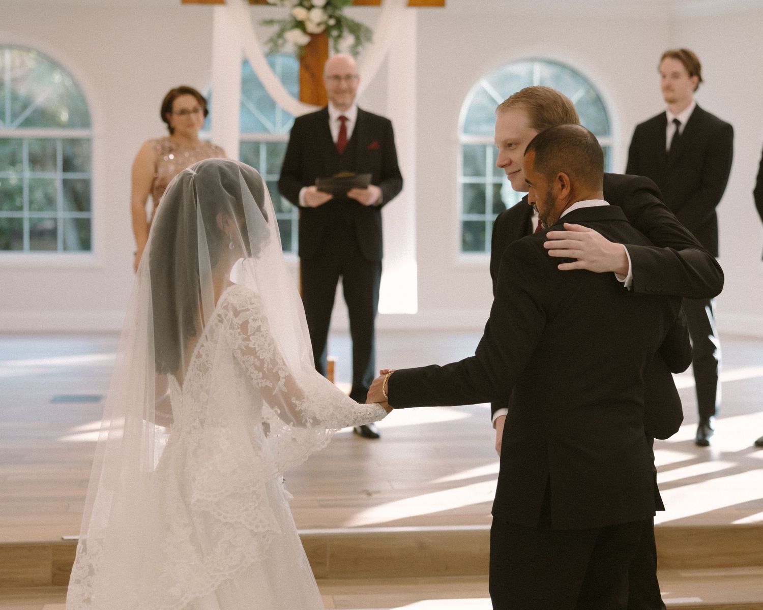 Bride is guided down the aisle and handed off during the ceremony, a meaningful and emotional moment surrounded by loved ones.