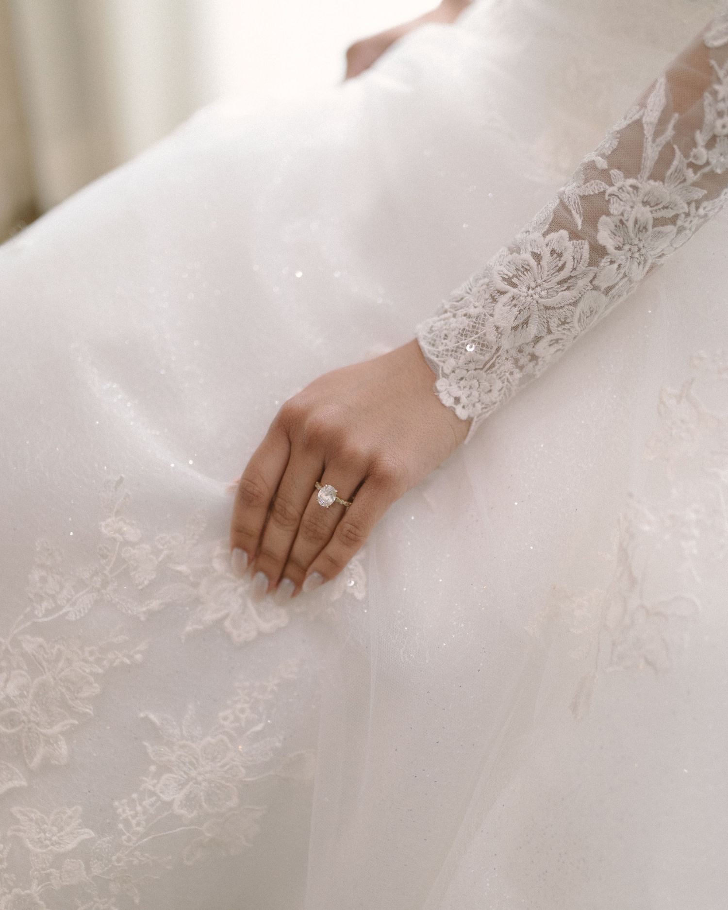 Bride in soft window light, framed through a doorway for an intimate, candid getting-ready moment.