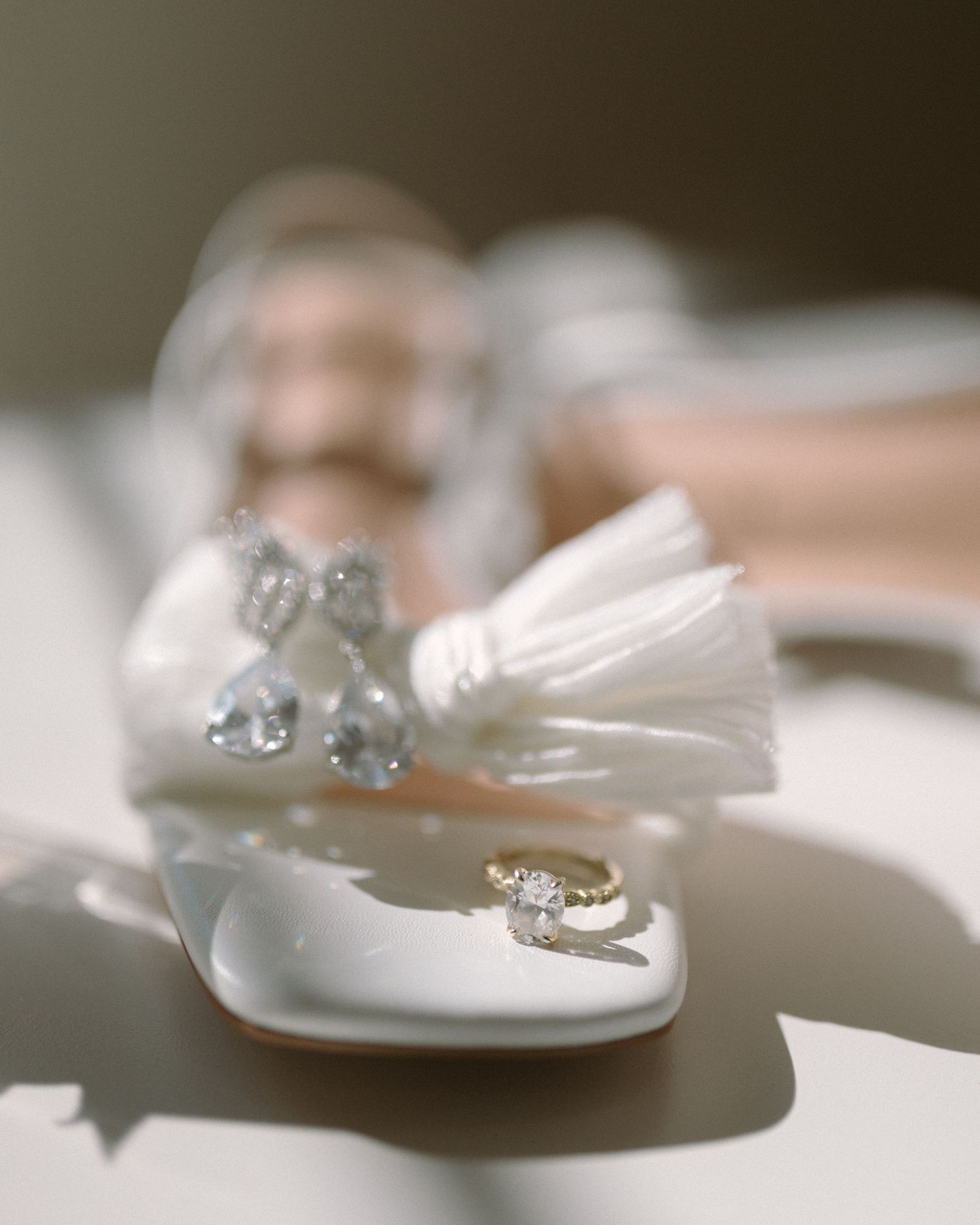 Bride in veil standing by soft drapery, a quiet and emotional portrait capturing anticipation before the ceremony.