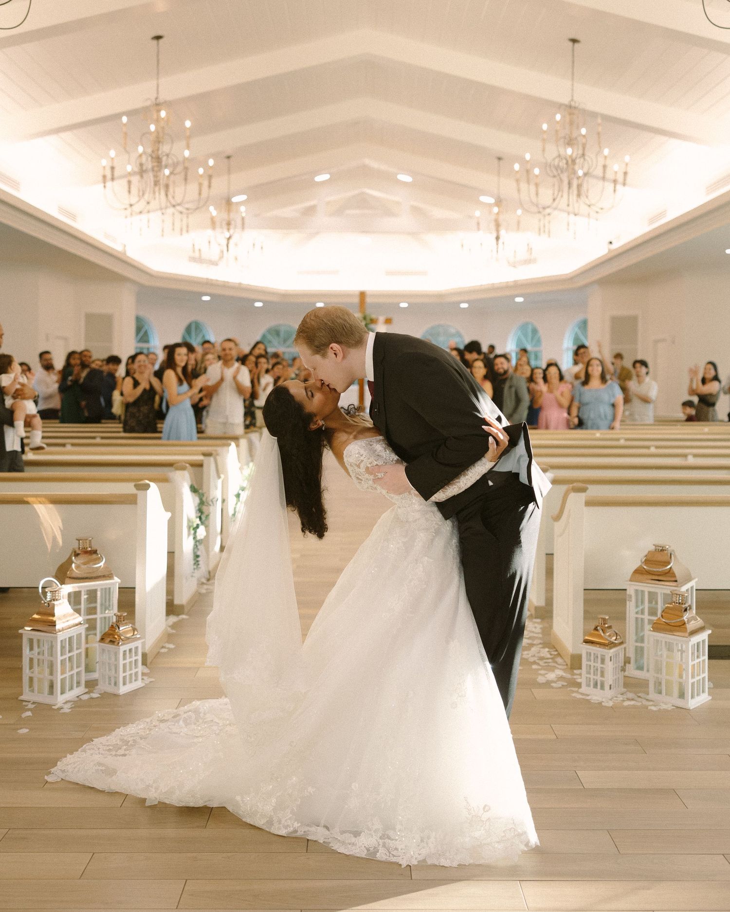 Newlyweds share their first kiss during the ceremony exit, surrounded by cheering guests.
