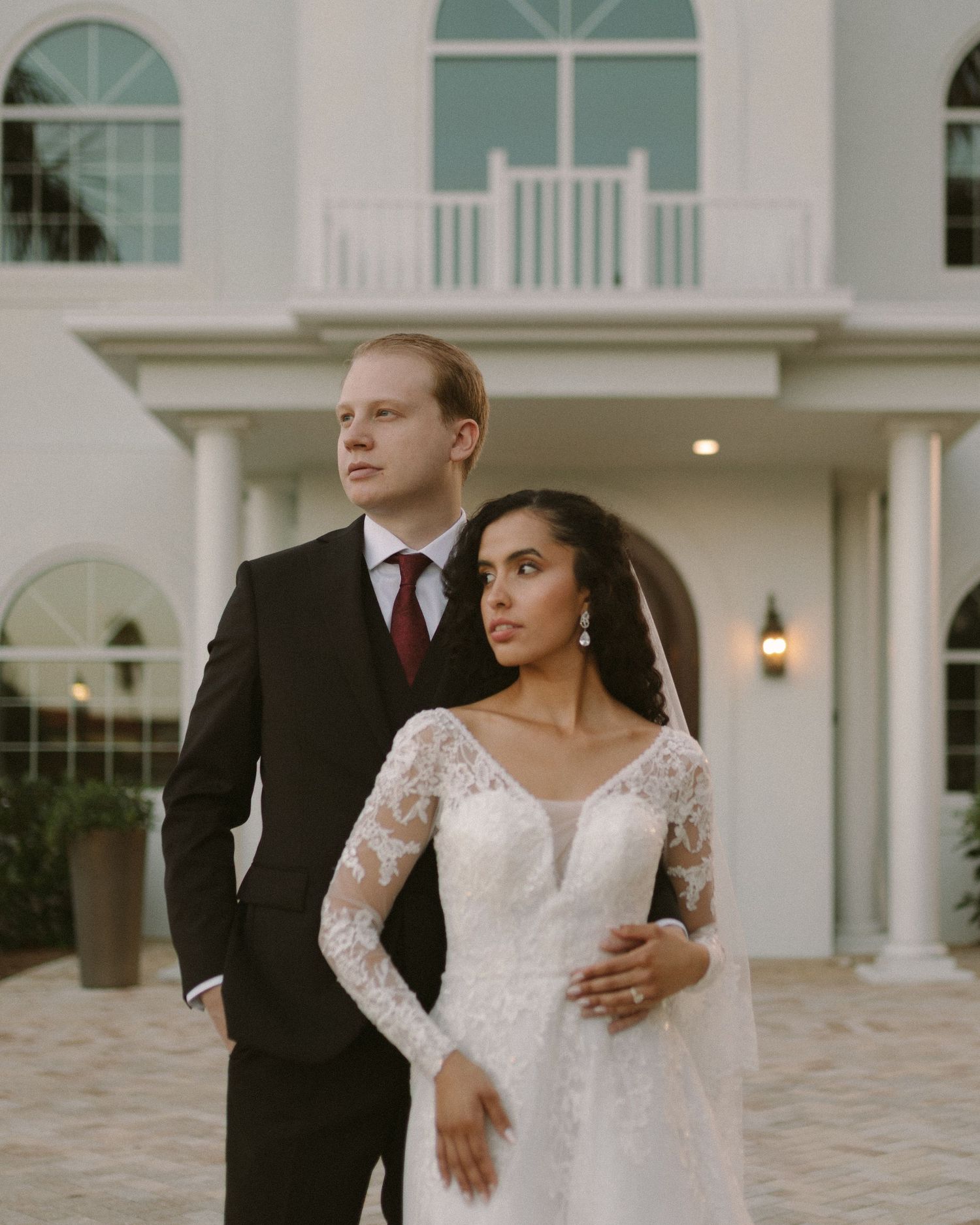 Bride and groom embrace in front of the venue, a timeless portrait with soft, natural tones.