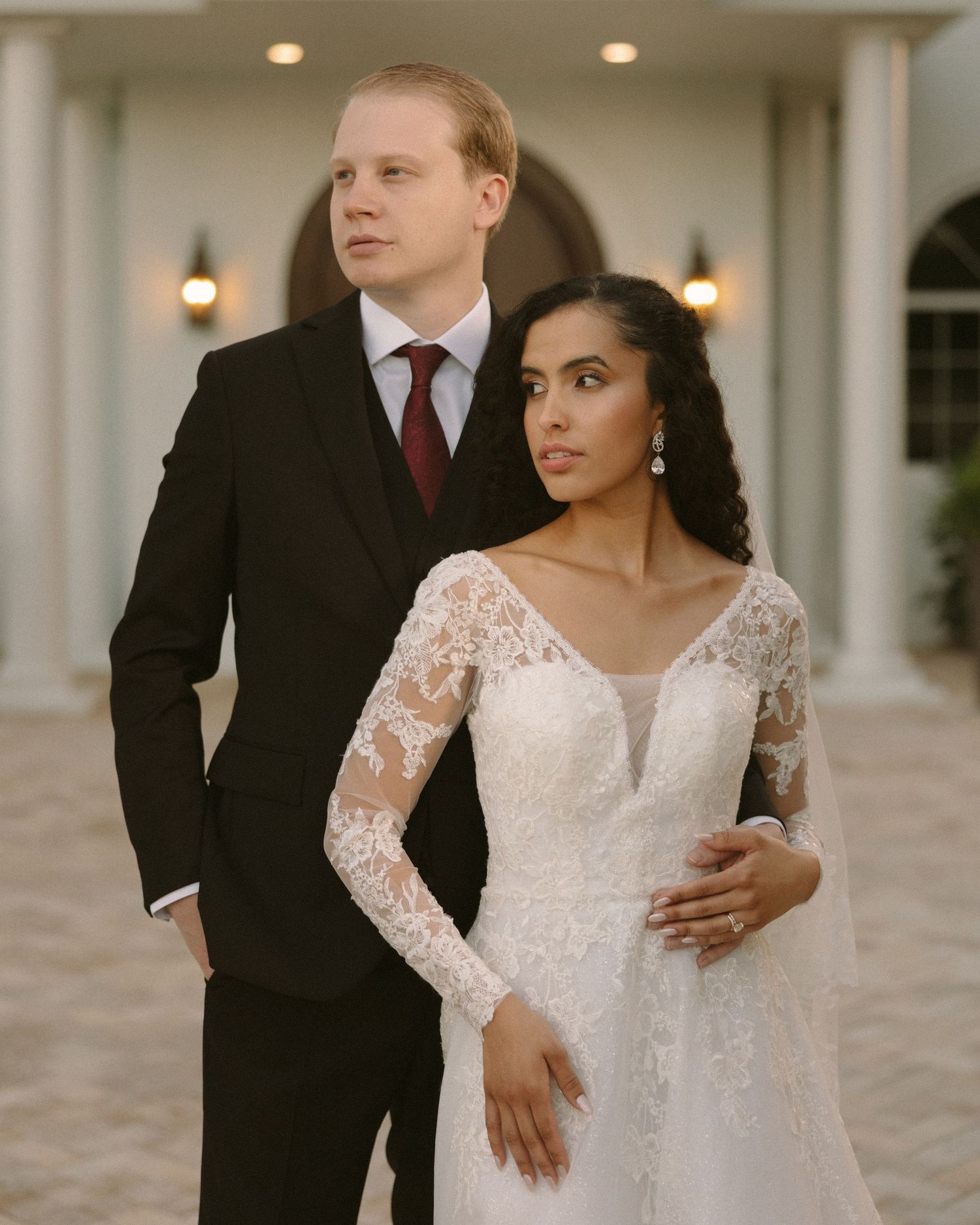 Bride and groom embrace in front of the venue, a timeless portrait with soft, natural tones.
