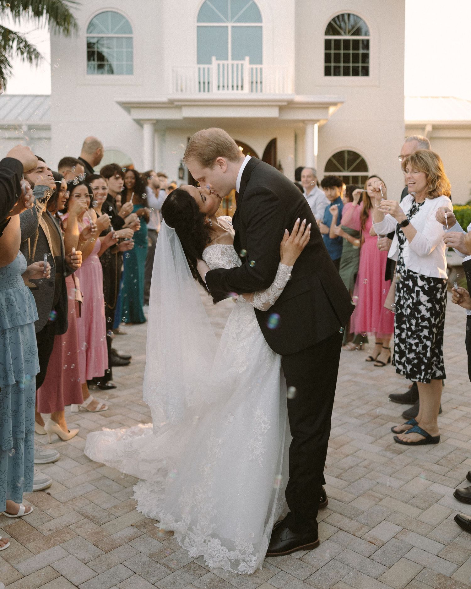 Newlyweds share their first kiss during the ceremony exit, surrounded by cheering guests.