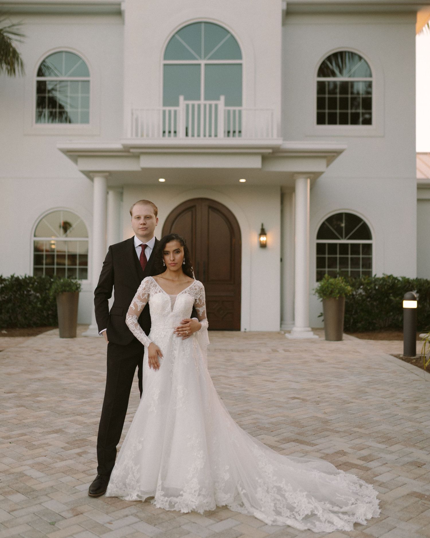Bride and groom embrace in front of the venue, a timeless portrait with soft, natural tones.