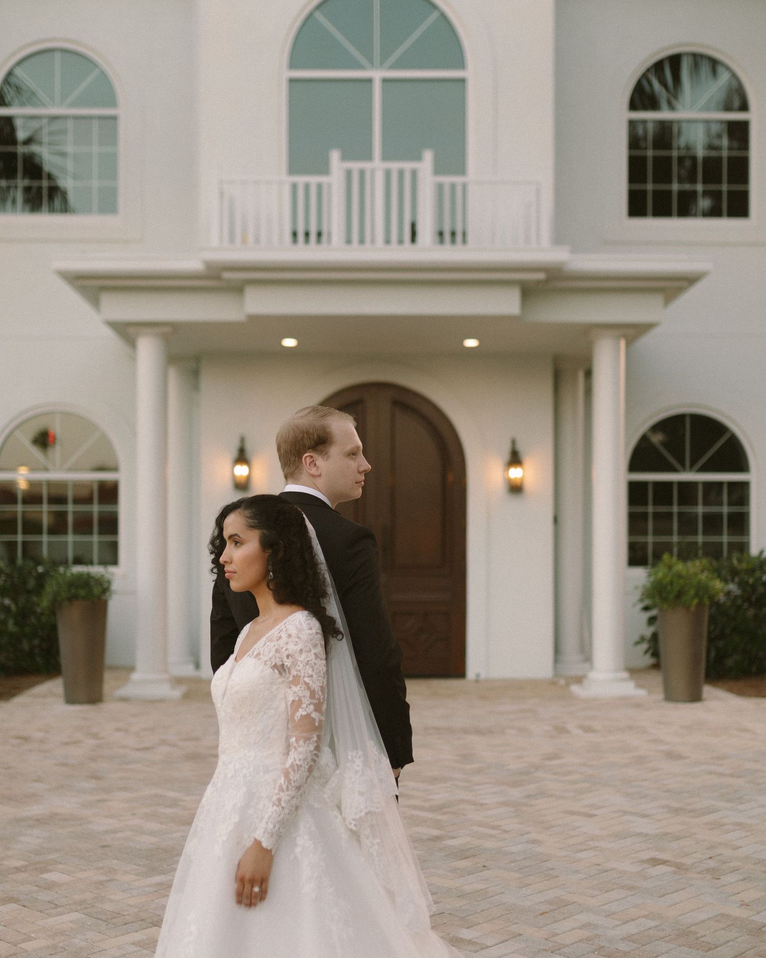 Bride and groom embrace in front of the venue, a timeless portrait with soft, natural tones.
