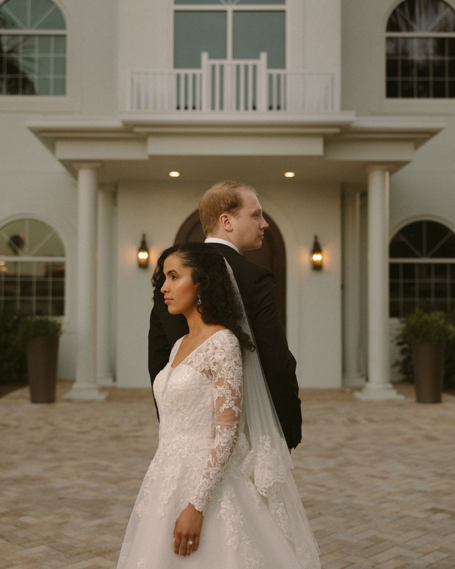 Bride and groom embrace in front of the venue, a timeless portrait with soft, natural tones.