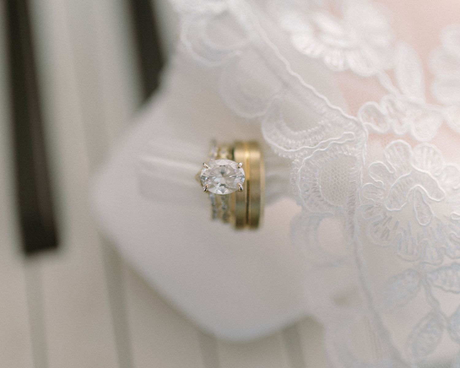 Bride in veil standing by soft drapery, a quiet and emotional portrait capturing anticipation before the ceremony.