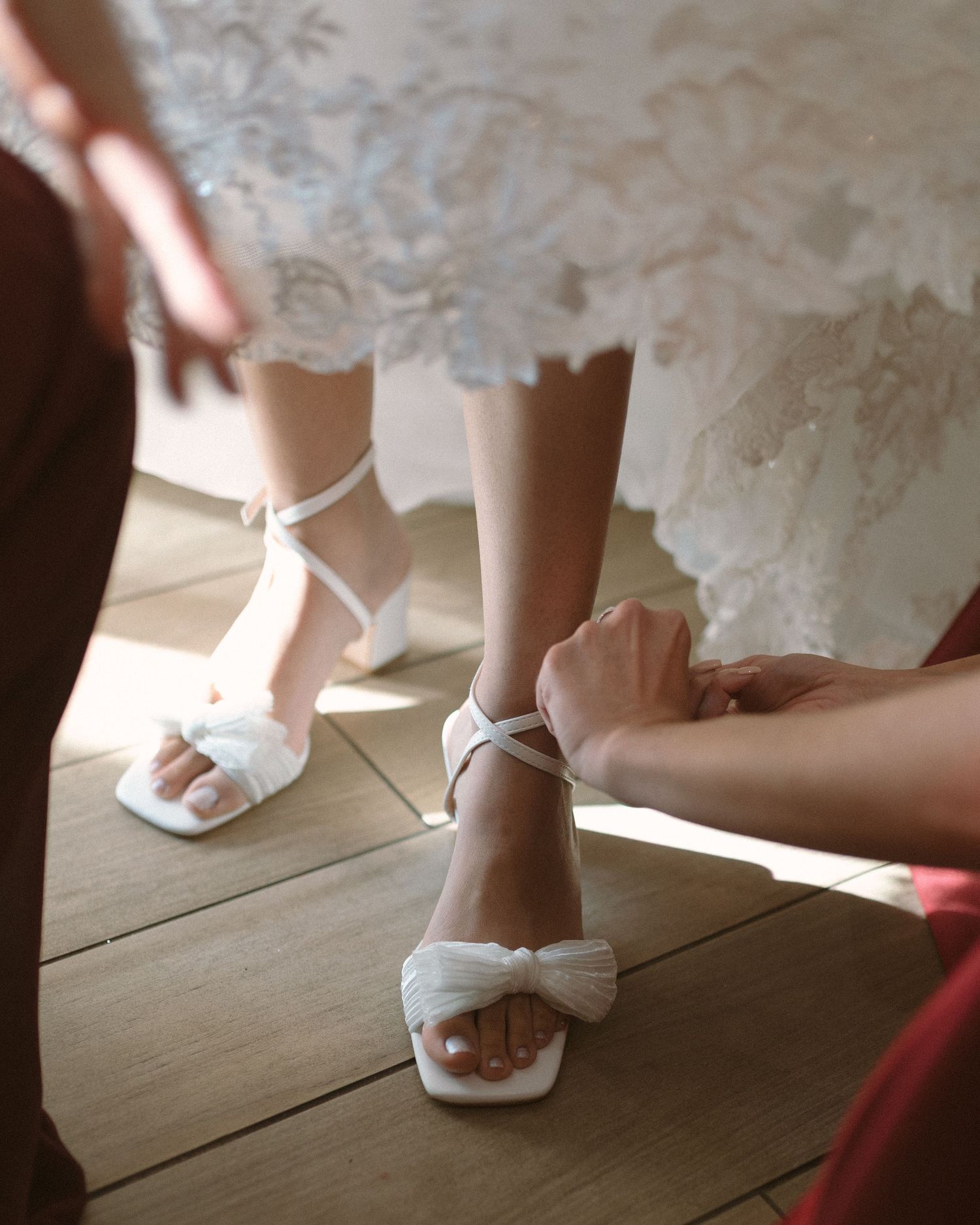 Bride in soft window light, framed through a doorway for an intimate, candid getting-ready moment.