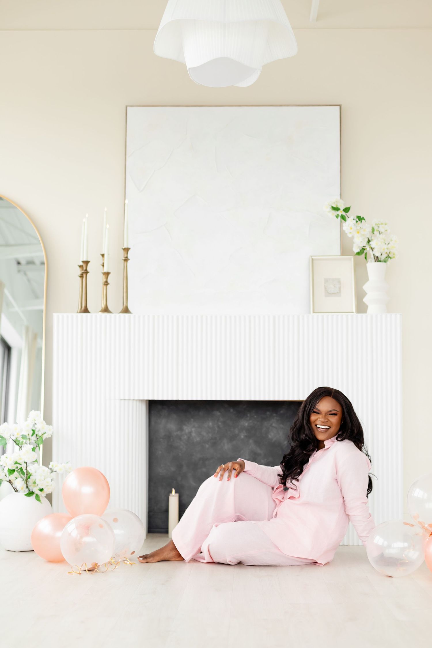 A bright and airy room decorated with pink pillows and balloons features a chalkboard wall and white decor elements.