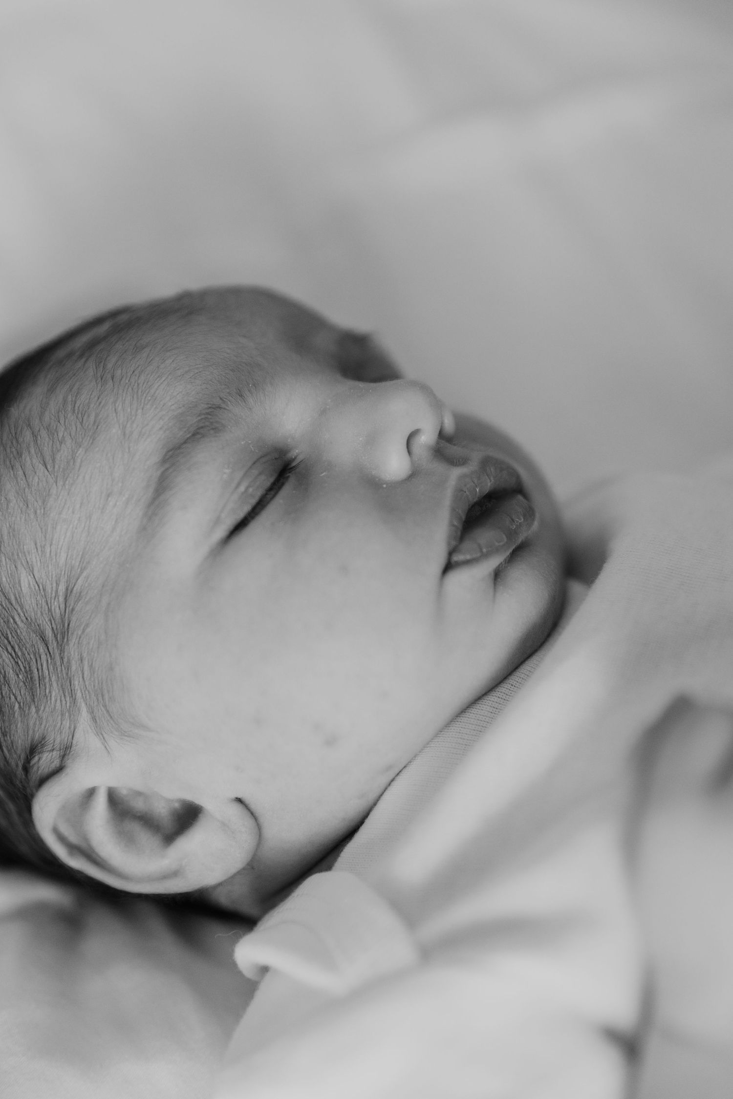 Close-up black and white portrait of a peaceful sleeping newborn baby.
