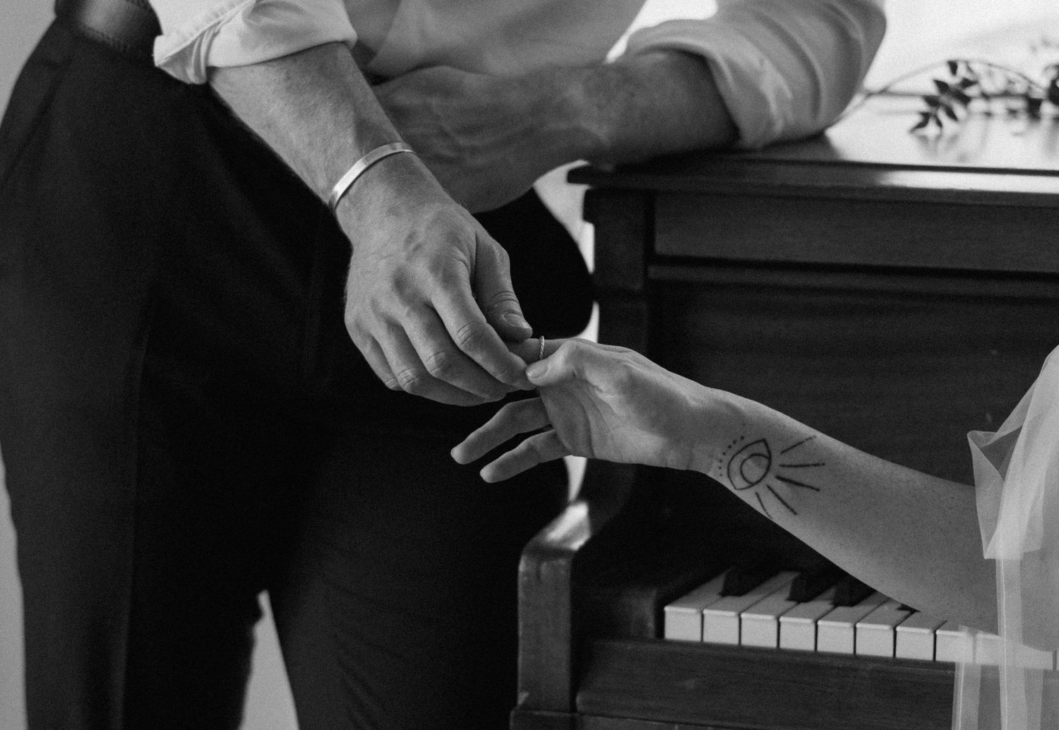 Black and white photo of hands playing piano keys with sheet music visible in the background.