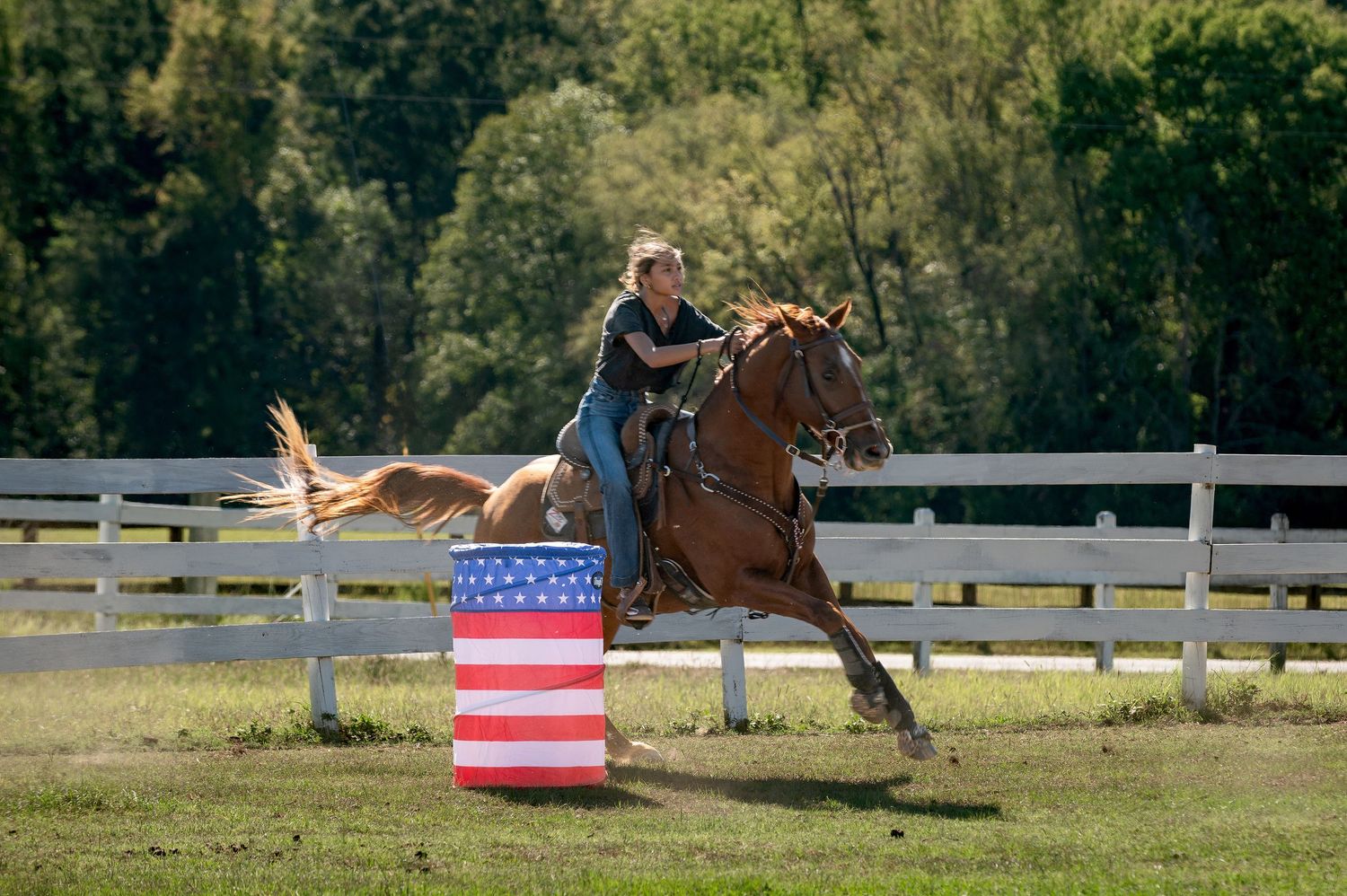 Barrel racer on a chestnut horse rounding a barrel at Tasch Stables during an equestrian competition in Georgia.
