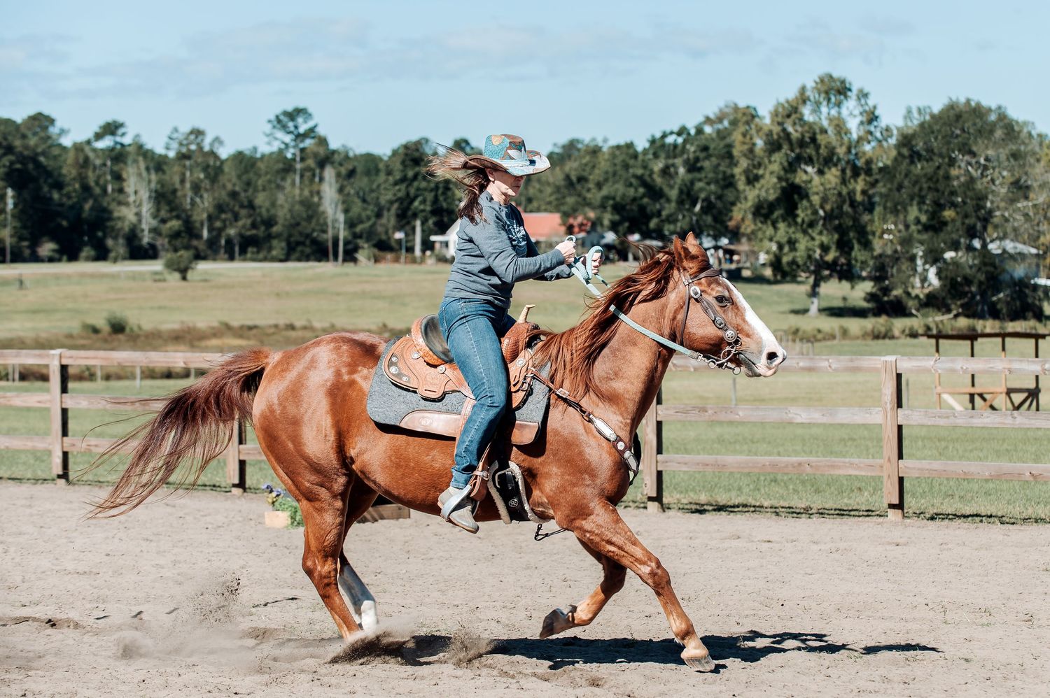 Cowgirl riding a chestnut horse through a sandy arena during Adams Family Fun Day in Warrenton, GA.