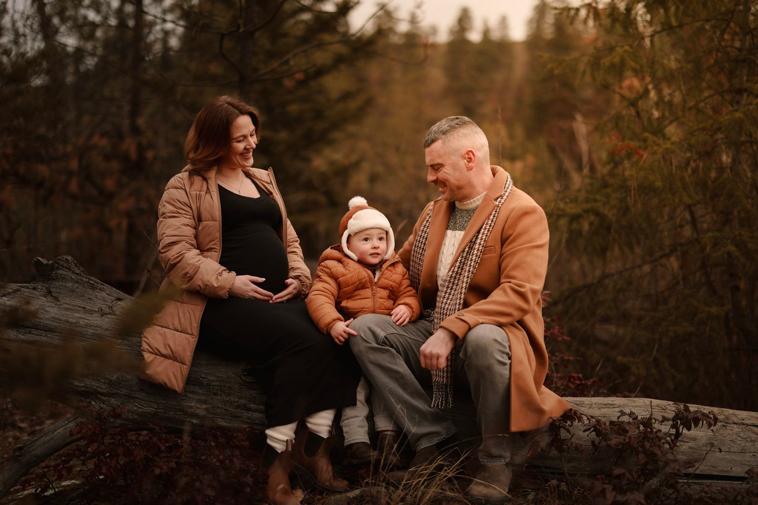 A family shares a warm moment together on a rock during sunset.