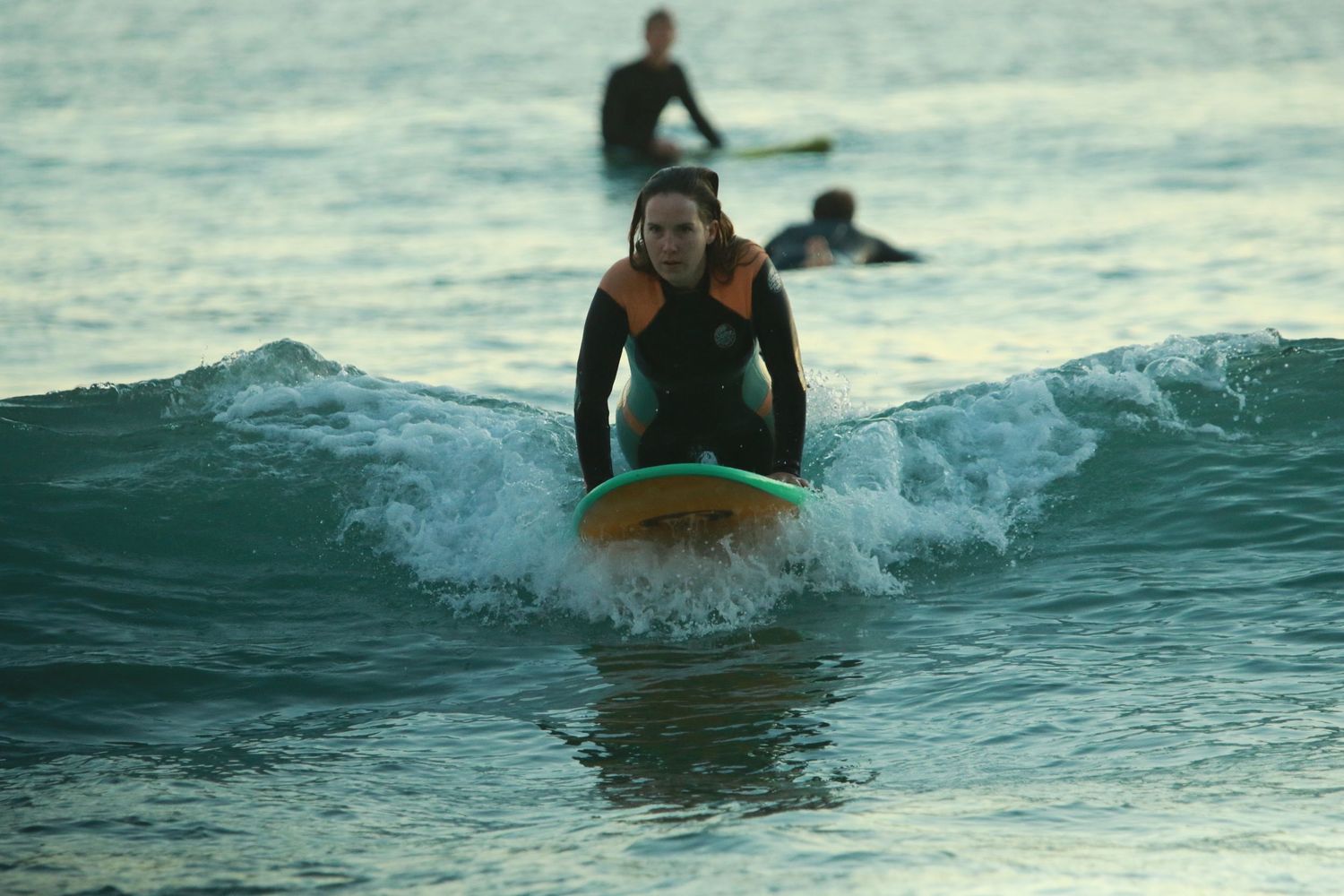 Surfer riding wave on yellow surfboard through white water splash.