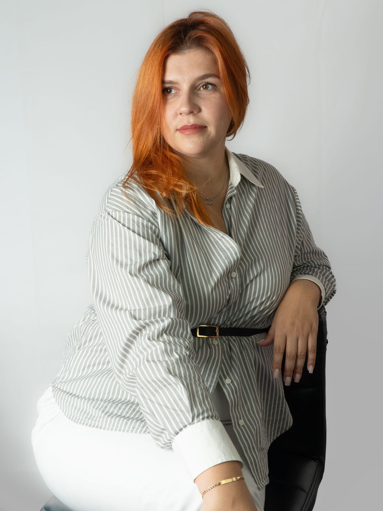 Professional studio portrait of redhead woman in striped button-down shirt.