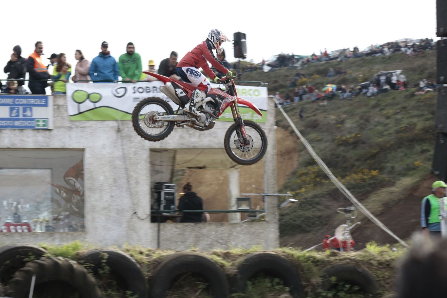 Motorcycle rider performing an impressive jump over concrete barriers during a motocross competition.