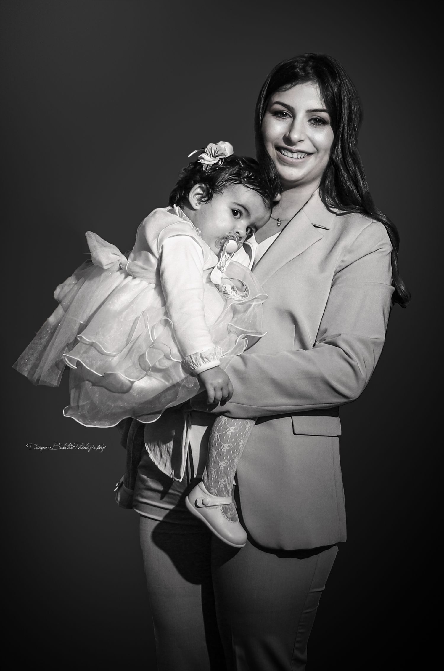 Black and white portrait of parent and child in formal attire during special occasion.