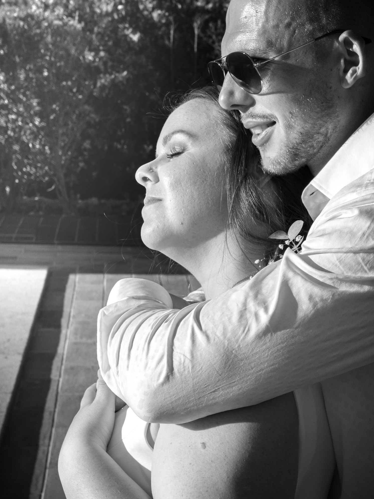 A tender black and white moment captured of a couple embracing in natural light.