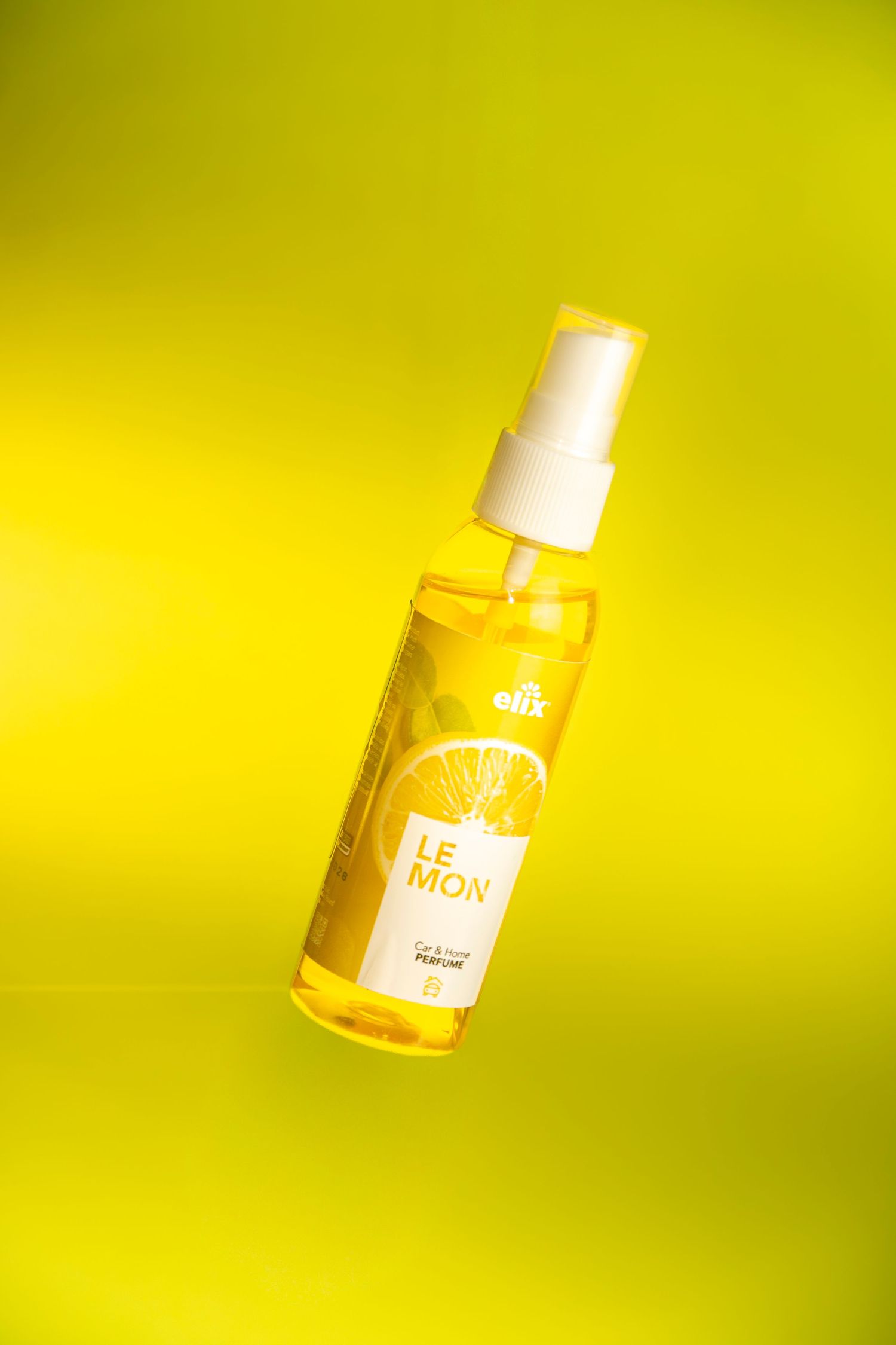 Lemon-scented spray perfume bottle with yellow liquid on a vibrant yellow background.